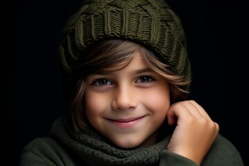Portrait of a smiling little boy in a knitted cap and scarf on a black background