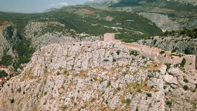 Aerial view of a coastal town Omis with a historic fortress overlooking the sea. Starigrad Fortica in Split-Dalmatia, Croatia.