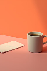 Coffee cup and note book on pink and orange background.
