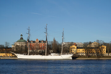 View of ship and buildings by river against clear blue sky