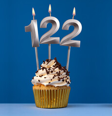 Burning candle number 122 - Birthday card with cupcake on blue Background