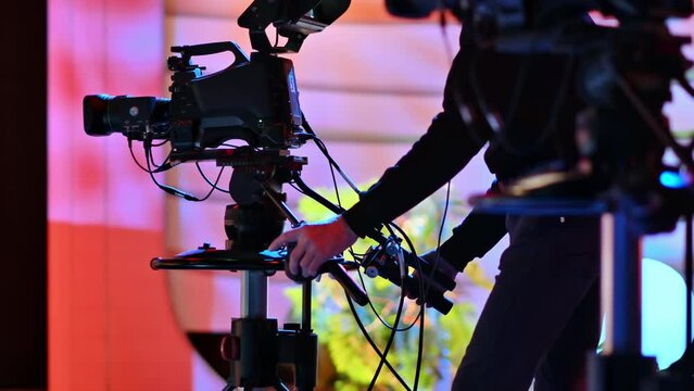 Cameraman filming a television show on a professional camera. Video production backstage in a dark studio