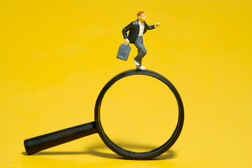 Miniature people toy figure photography. A boy pupil student running above magnifier glass....