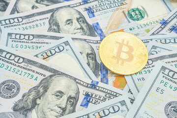 Gold Bitcoin on hundred dollars bills. Golden symbolic coin Bitcoin on banknotes of one hundred dollars. Cryptocurrency on US dollar bills. Digital modern method of payment. Exchange bitcoin cash