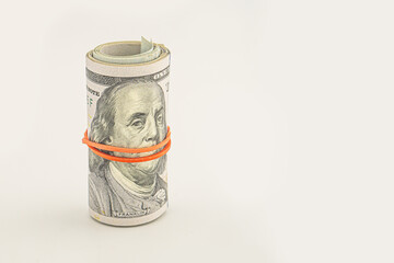 Dollar roll wrapped with red ribbon. 100 dollar bills on a roll isolated on white background. Rolled up money isolated on white background. Dollars isolated on white background.