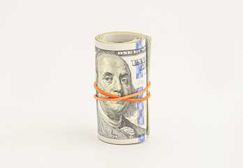 Dollar roll wrapped with red ribbon. 100 dollar bills on a roll isolated on white background. Rolled up money isolated on white background. Dollars isolated on white background.
