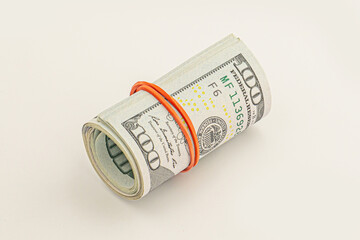 Dollar roll wrapped with red ribbon. 100 dollar bills on a roll isolated on white background. Rolled up money isolated on white background. Dollars isolated on white background.