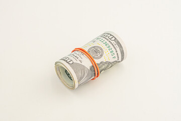 Dollar roll wrapped with red ribbon. 100 dollar bills on a roll isolated on white background. Rolled up money isolated on white background. Dollars isolated on white background.
