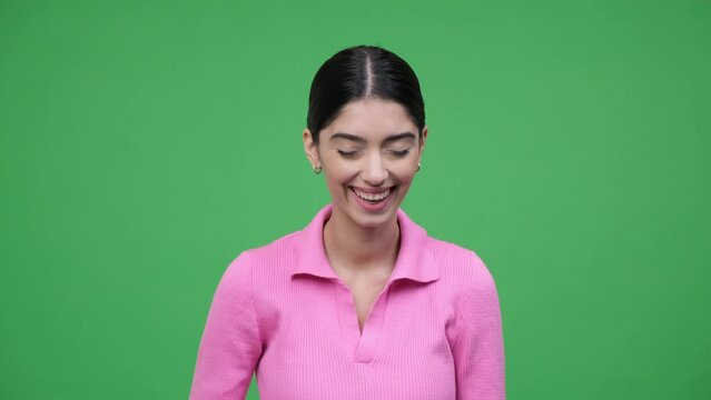 Positive portrait of a cheerful young Caucasian woman laughing, looking at camera against green background. Positive emotions, pleasure, good mood.
