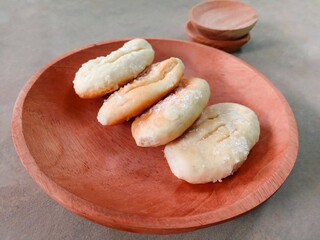 Cookies sprinkled with granulated sugar served on a wooden plate. bakpia. small dry bread topped...