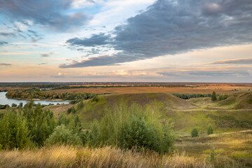 Fototapeta premium Evening landscape with sunset sky over the river, water meadows in the background