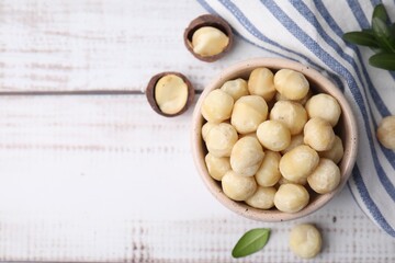Tasty peeled Macadamia nuts in bowl on light table, flat lay. Space for text