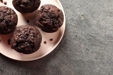 Delicious chocolate muffins on grey textured table, top view. Space for text