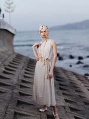 Beauty and Elegance by the Blue Water: A Fashionable Young Woman in a Stylish Dress Posing at the Beach