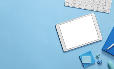 Modern tablet, stationery and keyboard on light blue background, flat lay. Space for text