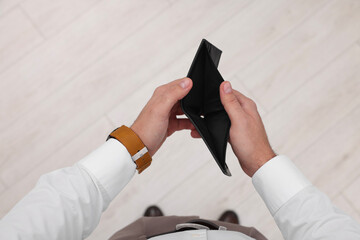 Man with empty wallet indoors, top view
