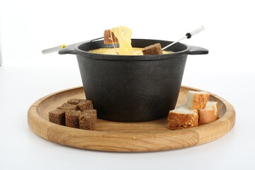 Fondue with tasty melted cheese, forks and pieces of bread isolated on white