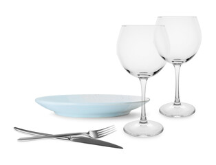 Clean plate, cutlery and glasses on white background