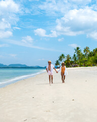 Koh Mook a young couple of caucasian men and Thai Asian woman walking at the beach in Thailand