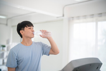 Happy healthy man are drinking water in the gym.After the exercise