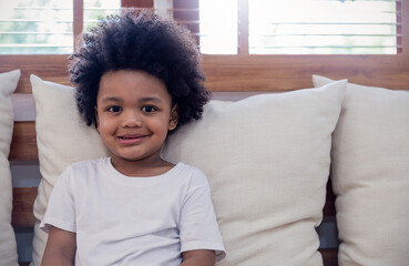 Portrait young happy little afro black boy rest on sofa living room background. Education back to...