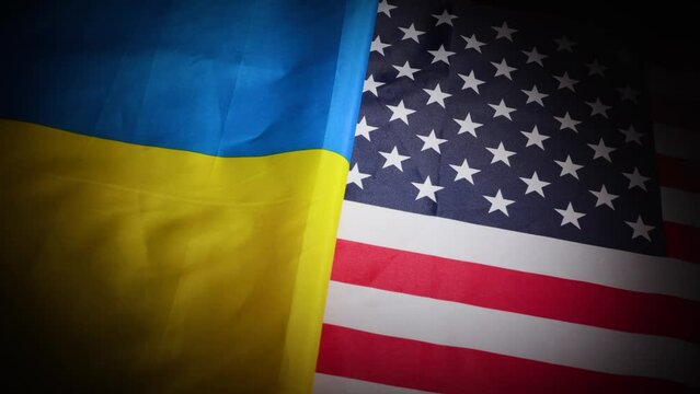 Dynamic turn of Ukraine and the United States national flags with vignette