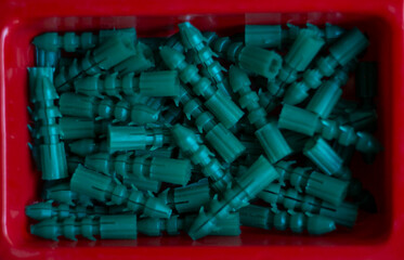 close-up de taquetes de plastico de color verde en recipiente rojo