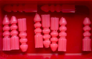 close-up de taquetes de plástico de color rosa en recipiente rojo