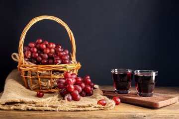 Red grape juice in a glass placed on a wooden table or red wine, a delicious natural healthy juice drink. With a bunch of fresh red grapes from the garden