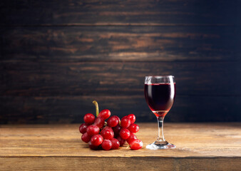 Red grape juice in a glass placed on a wooden table or red wine, a delicious natural healthy juice drink. With a bunch of fresh red grapes from the garden