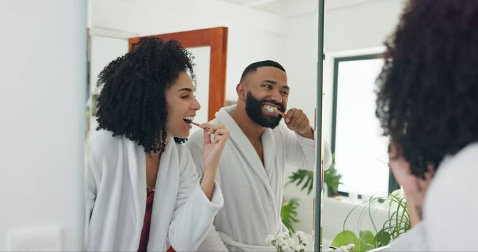 Happy couple, brushing teeth and dental care in morning for hygiene together in bathroom at home. Man and woman smile with toothbrush for tooth whitening, grooming or getting ready in mirror at house