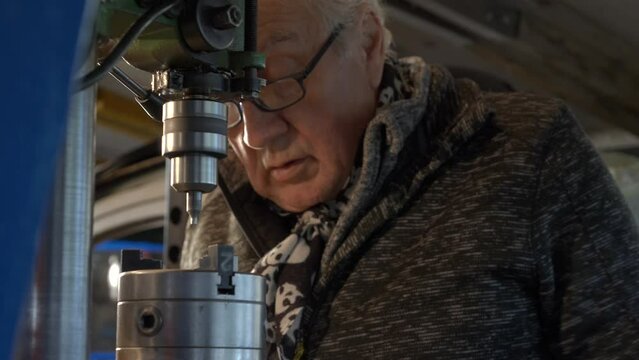 Old caucasion worker starting drilling machine in an old workshop