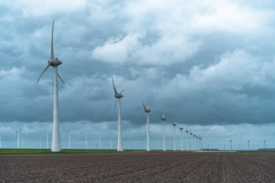 Wind turbines in a field under a stormy sky in springtime
