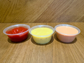 Closeup of various dipping sauces for French fries including ketchup, honey mustard, and fry sauce