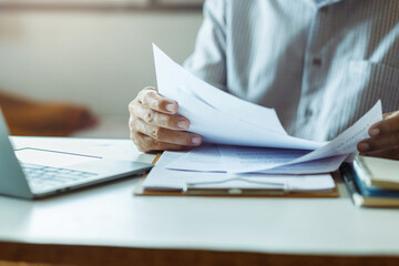 Asian businessman reviewing document reports at office workplace with computer laptop. legal...