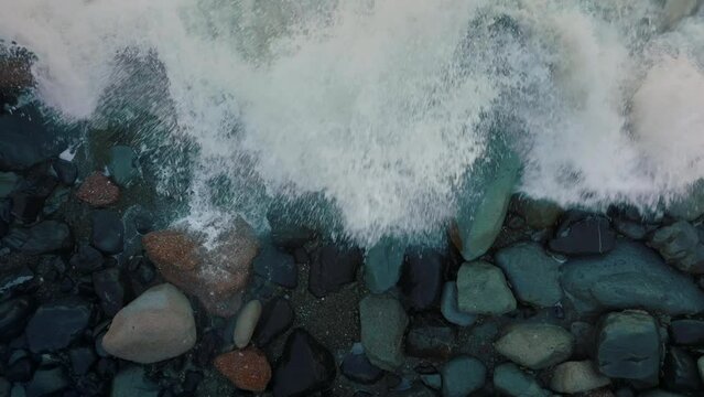 Aerial: Waves crashing over boulders in slow motion. Oamaru, Otago, New Zealand.