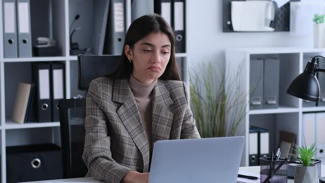 Puzzled, troubled caucasian woman office worker in doubt shrug shoulder working with laptop at desk in the modern office environment.