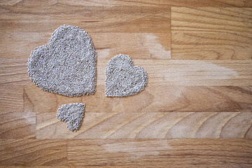 Three white chia seed  shaped hearts on a wooden board with negative space 