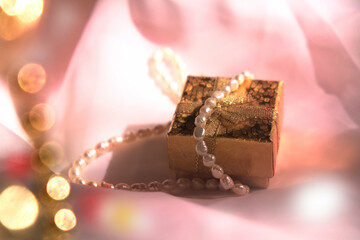 String  with natural pearls and  golden gift box and sniny  golden bokeh. Wedding, Birthday. Luxury ceremony