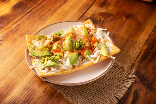 Fried wheat flour toast with pickled pork skin, sour cream and vegetables with hot sauce, in Mexico is called Chicharron preparado, traditional street food, pickled pork skin are known as Cueritos.
