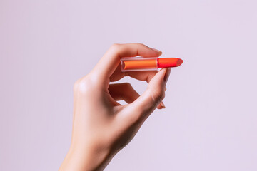 Hand holding orange lipstick isolated on white background, beauty