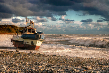 View of the beached ship. The wreck of a yacht in stormy weather. A shipwreck on the beach. An old...