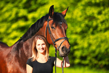 Horse and girl head portraits against a green background in the sunshine