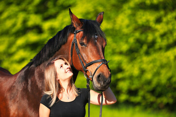 Obraz premium Horse and girl head portraits against a green background in the sunshine