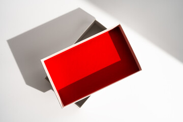 White square gift box mockup on white background, harsh shadows, red inside. From above, top view, minimalist concept, mock up, luxury