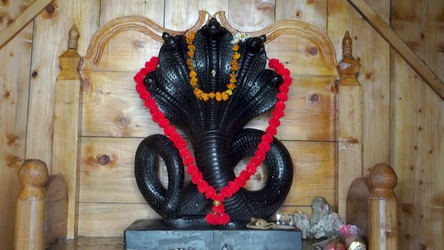 June 28th, 2023, Nagthat, Uttarakhand, India. Hindu Deity Nag Devta or the Serpent God black stone figure in a temple with a wooden interior.