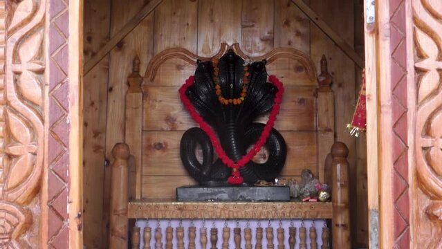 June 28th, 2023, Nagthat, Uttarakhand, India. Hindu Deity Nag Devta or the Serpent God black stone figure in a temple with a wooden interior.