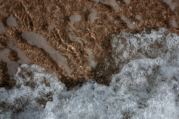Abstract view with sea waves texture. Foam of sea waves in color abstraction. The structure of the sea surf in shallow water is specially tinted in different colors. View from above.