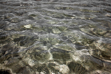View of clear water with a slight rough sea. Small waves on the sea on a sunny day. Seabed in shallow waters in calm conditions.