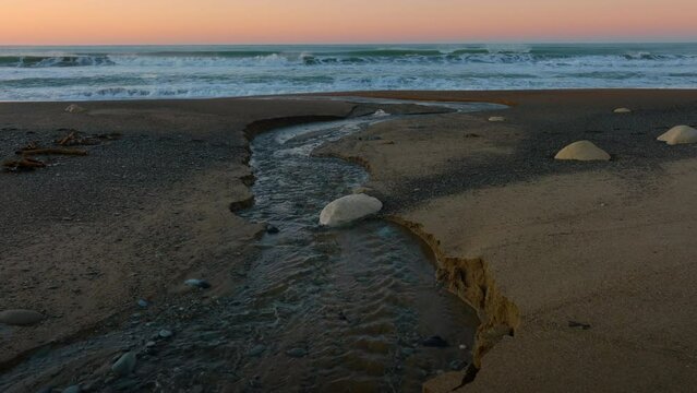 Aerial: Ocean beach surf and beach in sunrise. Oamaru, Otago, New Zealand.